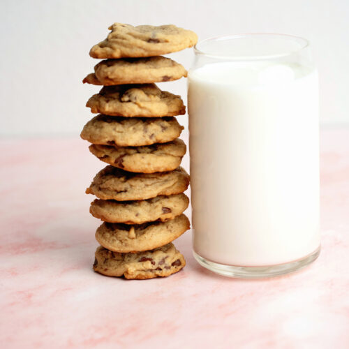 Stack of chocolate chip cookies next to a cup of milk